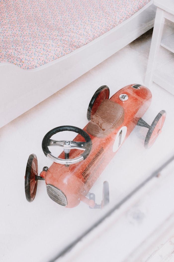 A nostalgic model red car captured indoors with a bright and airy ambiance. Ideal for vintage and childhood themes.